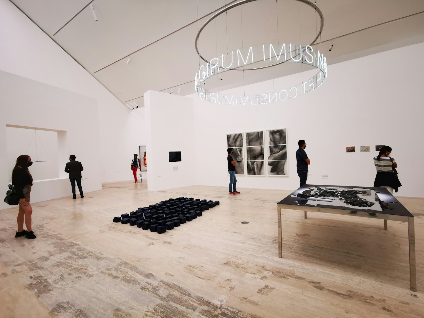 Visitors walk through a gallery viewing contemporary art and sculptures.