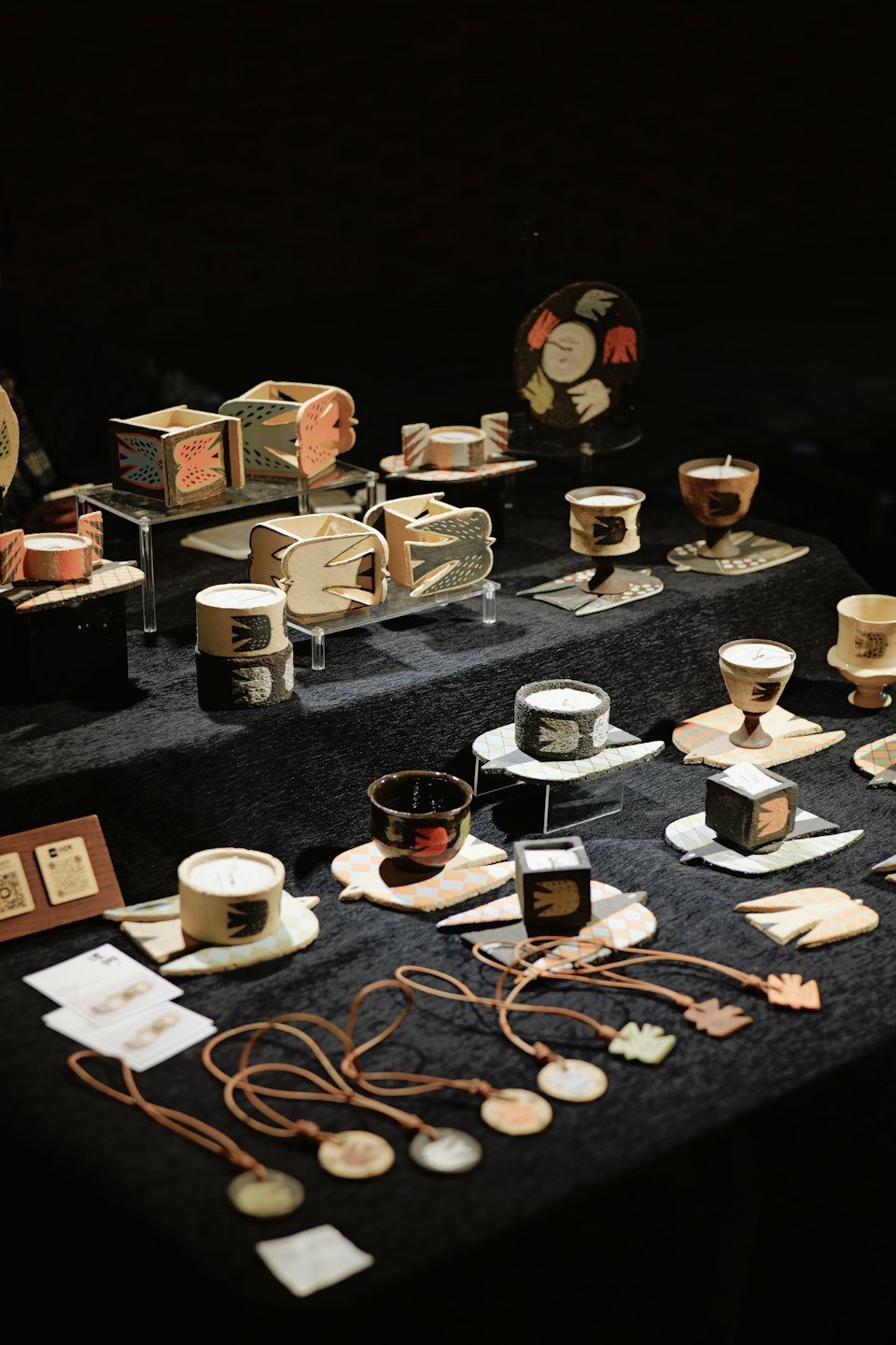 Handcrafted ceramic birds and containers on a dark display table.