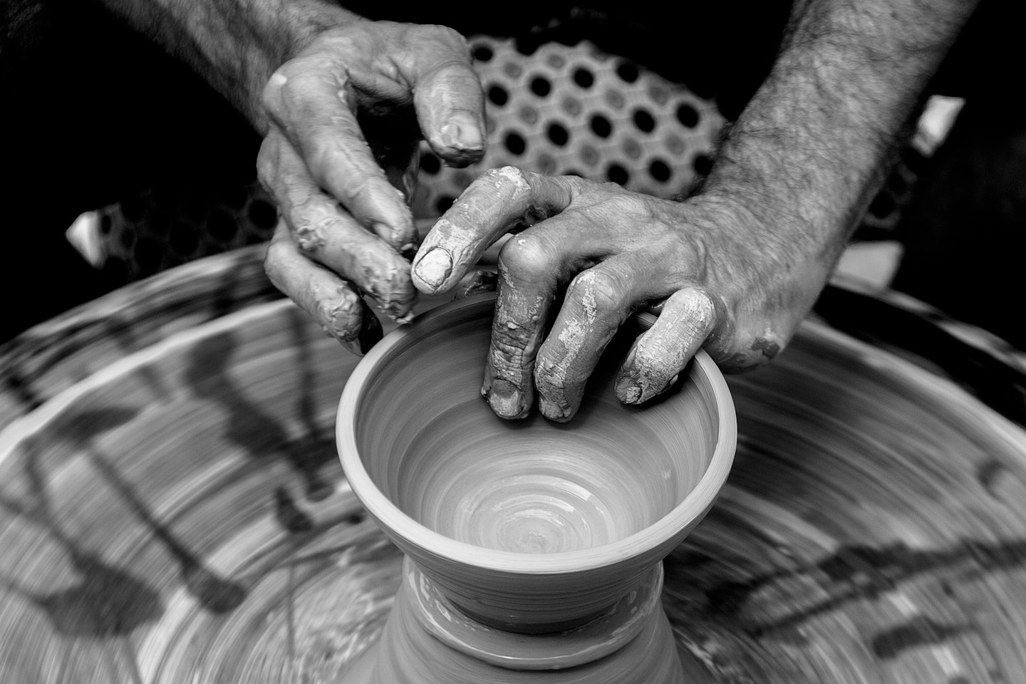 Potter's hands shaping wet clay on a spinning wheel.