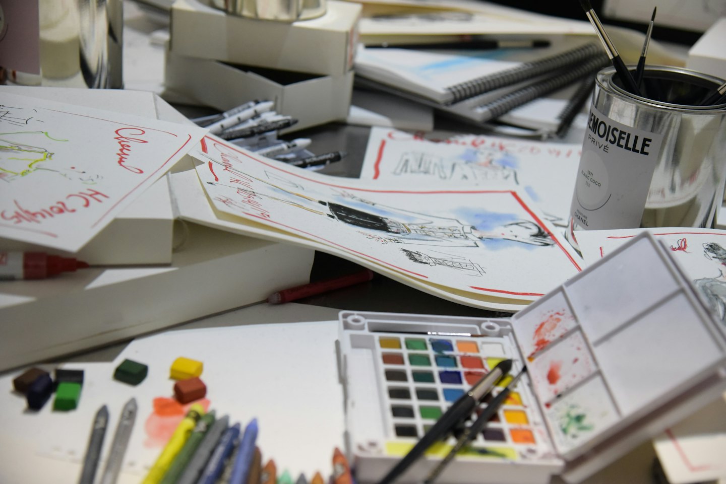Fashion sketches and art supplies scattered across a designer desk.
